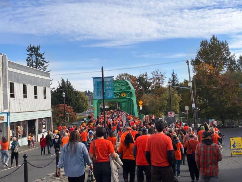 People dressed in orange for TRC day walk down the street.